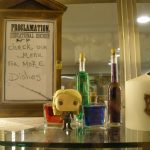 Φωτογραφία: Βιτρίνα με μπουκαλάκια με φίλτρα, μινιατούρα της Λούνα, κερί Γκρίφιντορ και την επιγραφή Check our menu for more dishes σε στυλ εντολής από την Άμπριτζ